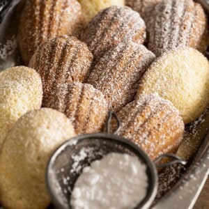 A tray of madeleine cookies with powdered sugar.