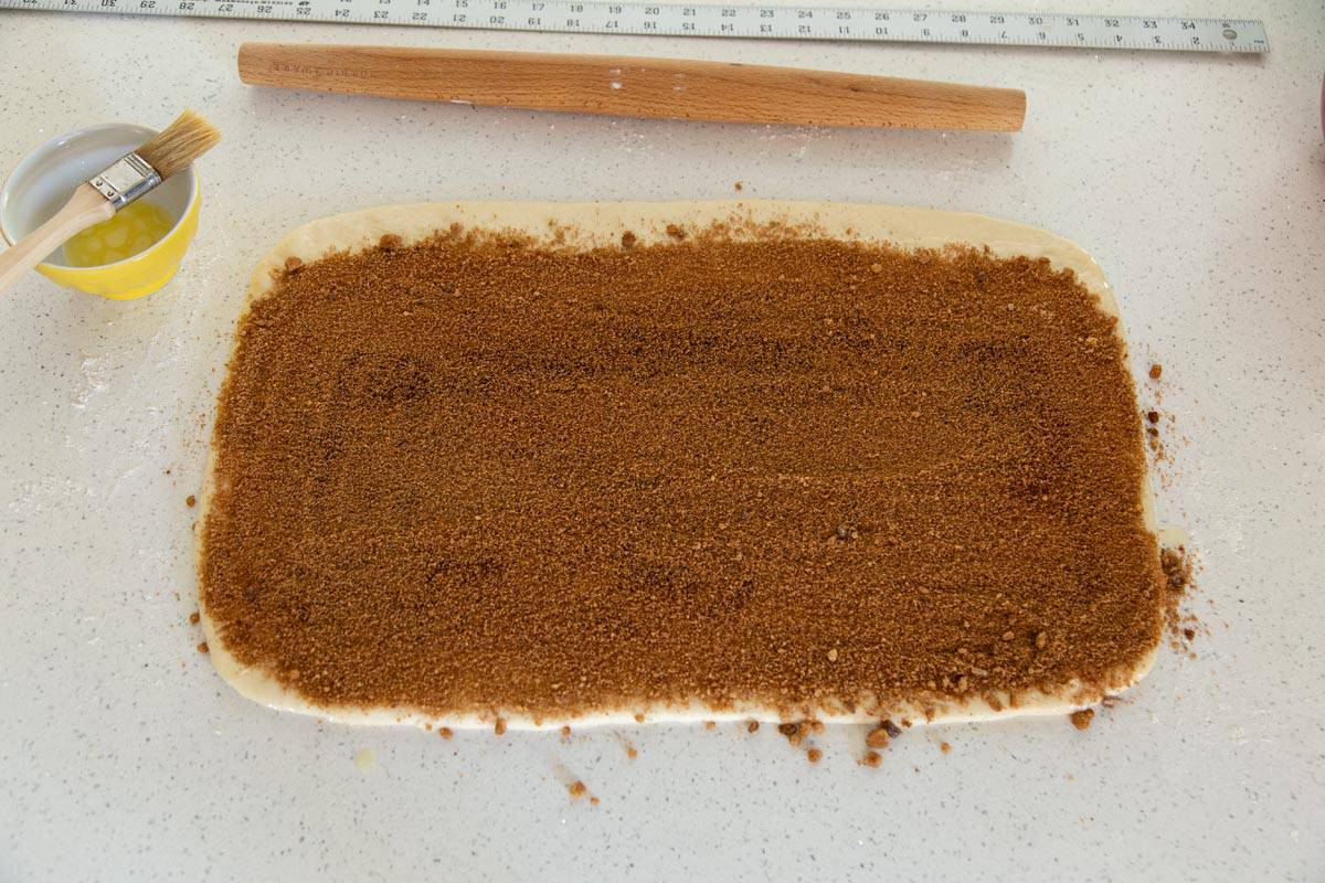 Cinnamon sugar is spread on top of the dough rectangle.