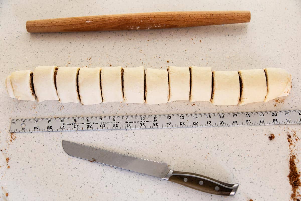 Cutting the log of dough into cinnamon rolls.