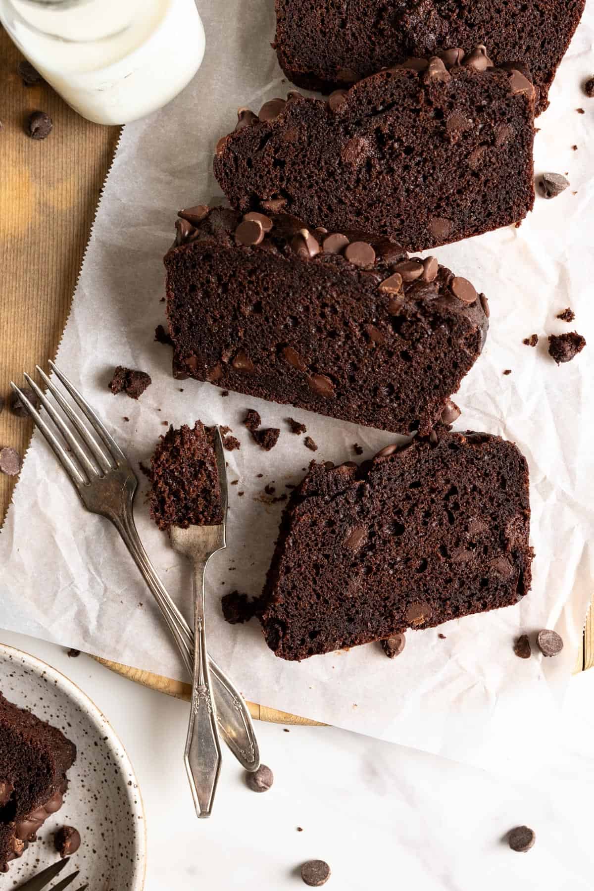 A few slices of chocolate loaf cake laying on top of parchment paper, a couple forks on the side.