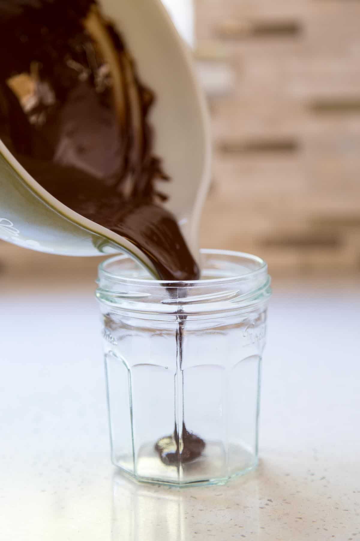 Pouring melted chocolate into a jar.