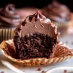 Chocolate ganache frosting on a chocolate cupcake split in half.
