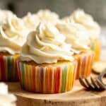 Pineapple cupcakes topped with pineapple buttercream frosting sitting on a wooden board.
