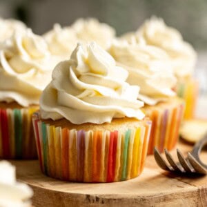 Pineapple cupcakes topped with pineapple buttercream frosting sitting on a wooden board.