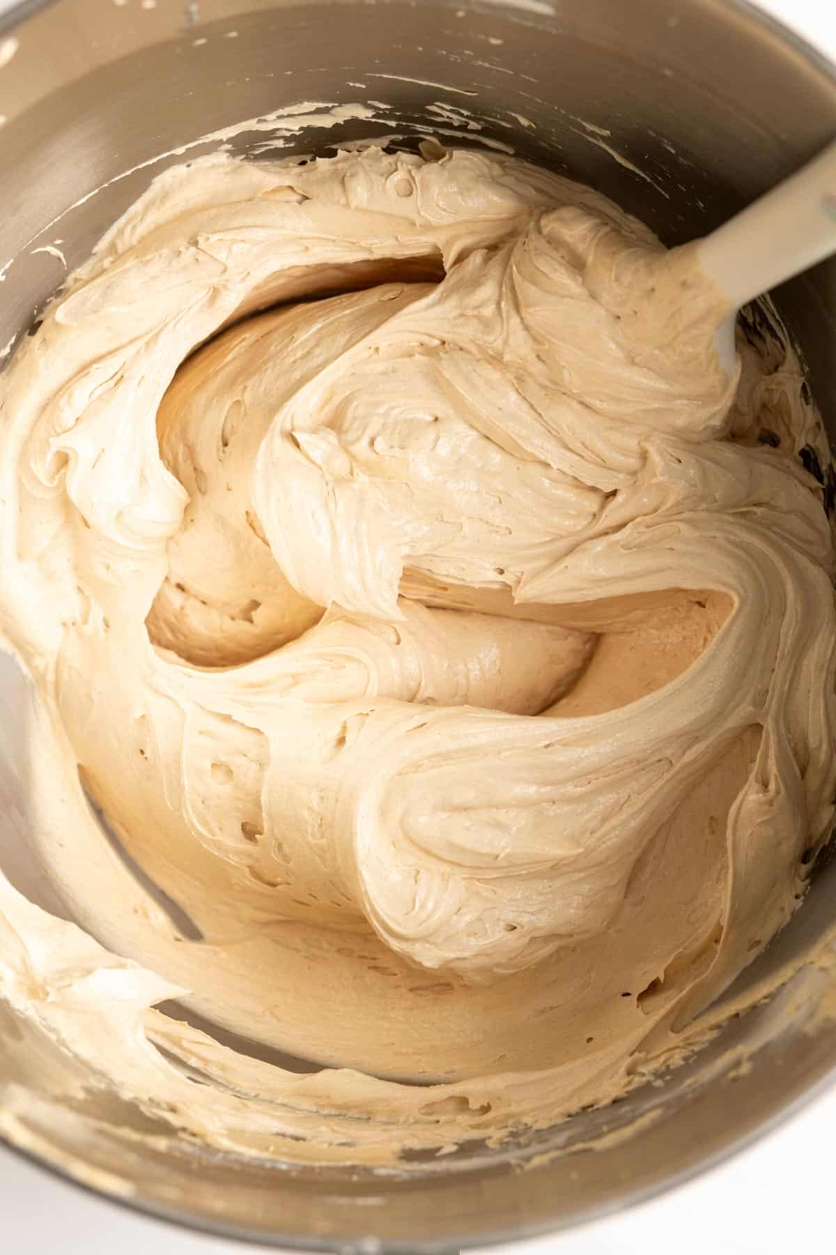 Creamy biscoff buttercream in a mixing bowl with a spatula.