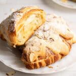 A half miso almond croissant resting on another on a white plate.