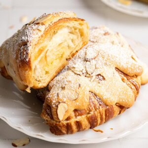 A half miso almond croissant resting on another on a white plate.
