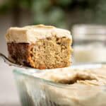 A cake server lifting a piece of miso banana cake from a glass dish.