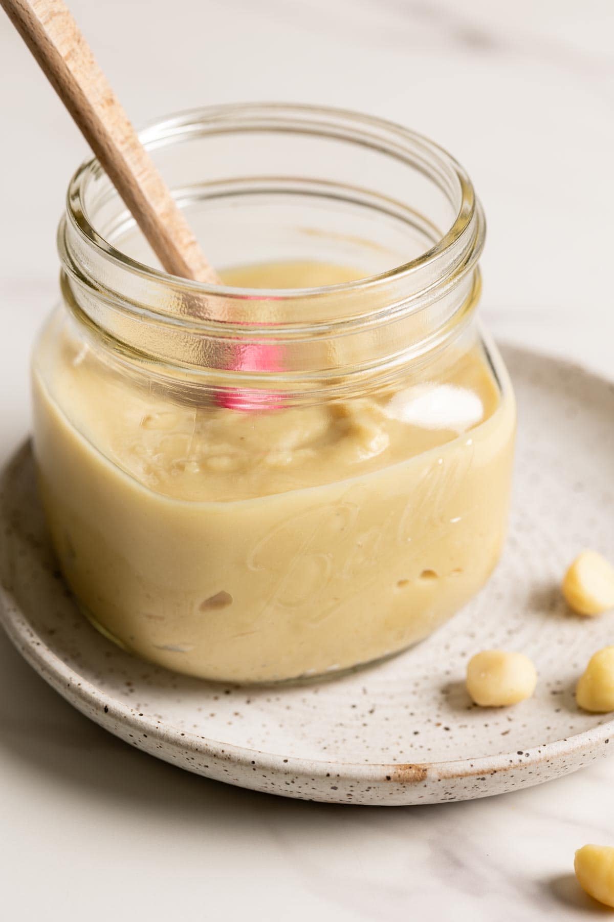 Macadamia butter in a glass jar on a plate.