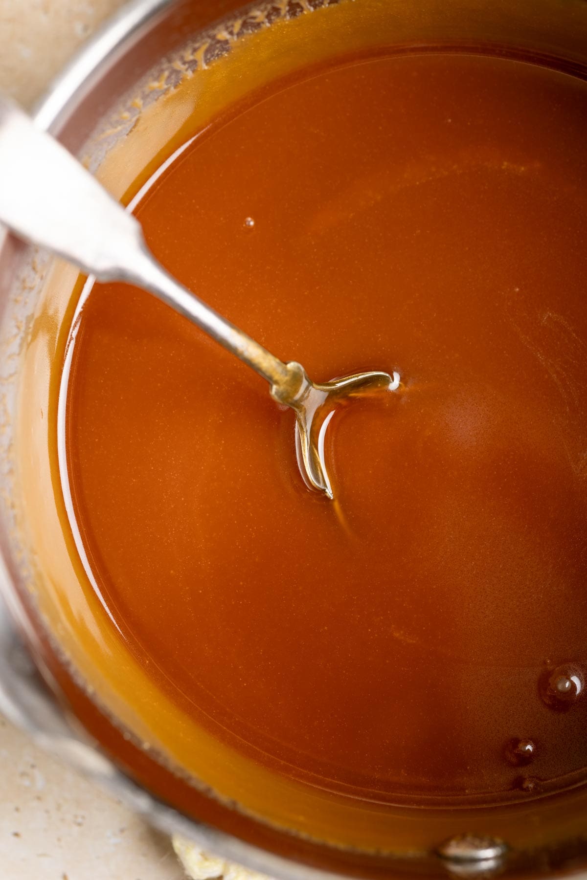 Miso caramel in a sauce pan with a spoon in it.