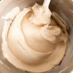 Creamy cinnamon cream cheese frosting in a stand mixer bowl with a spatula.