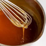 Coconut caramel sauce falling off a whisk into a pan.