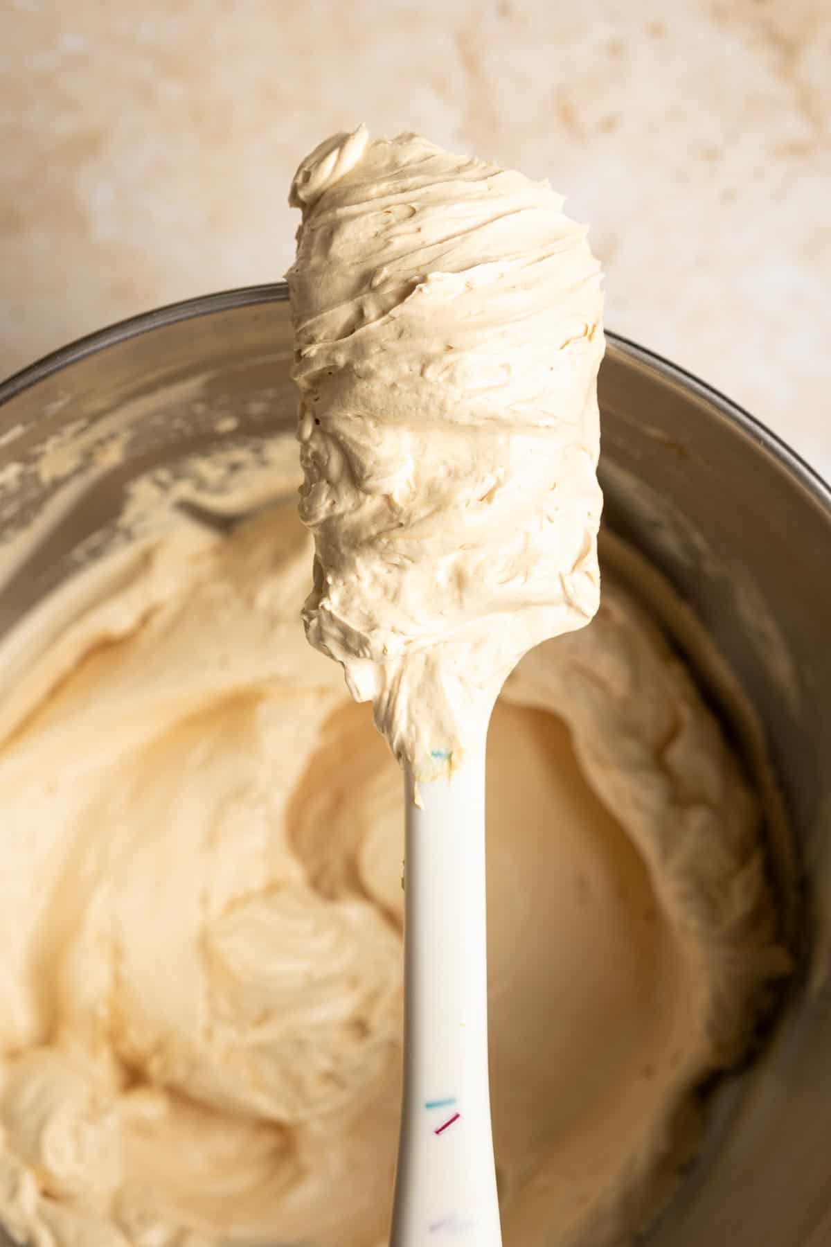 Miso caramel buttercream frosting on a spatula, resting on top of a mixing bowl.