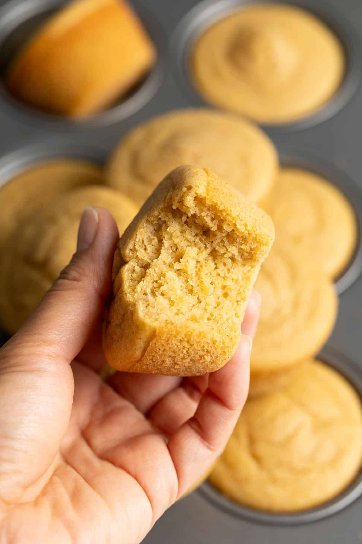 A hand holding up a half eaten mochi cornbread.