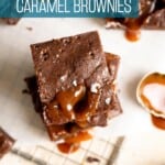 A stack of caramel brownies with sea salt flakes on top.