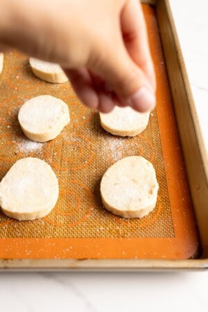 Sprinkle sugar topping on top of macadamia shortbread for baking.