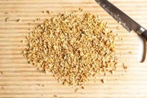Chopped walnuts on a wooden cutting board.