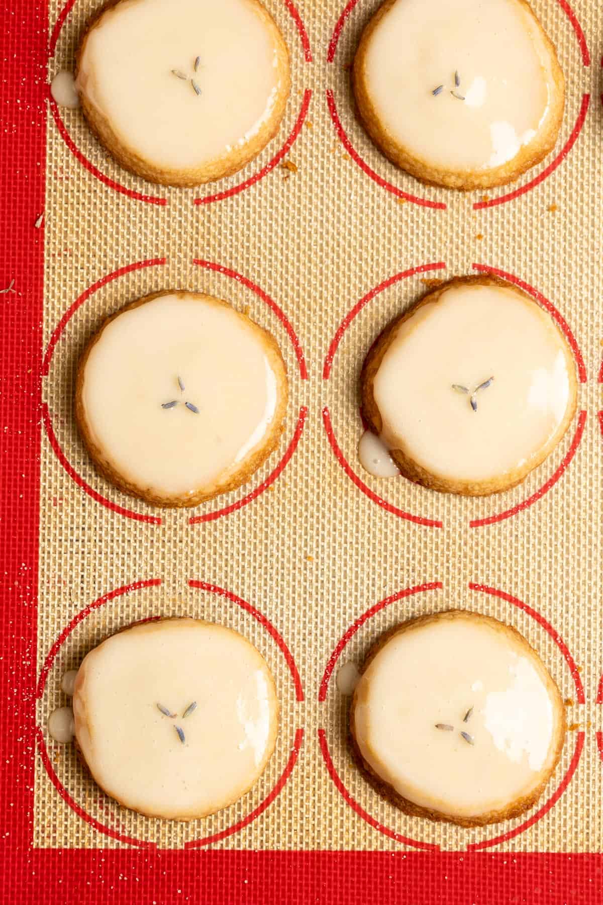 Glazed honey lavender shortbread cookies on a lined baking sheet.