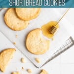A few macadamia shortbread on a piece of parchment paper next to a honey dipper.