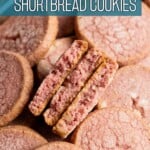 Three halved raspberry shortbread cookies nestled in a tray of cookies with text overlay.