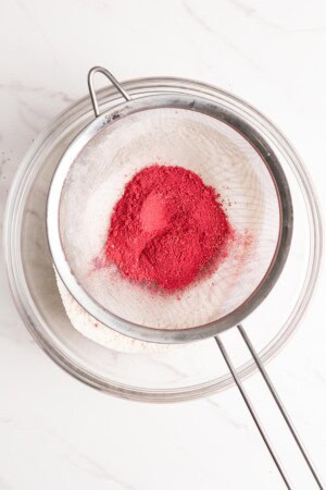 Sift raspberry powder into a bowl with other dry ingredients.