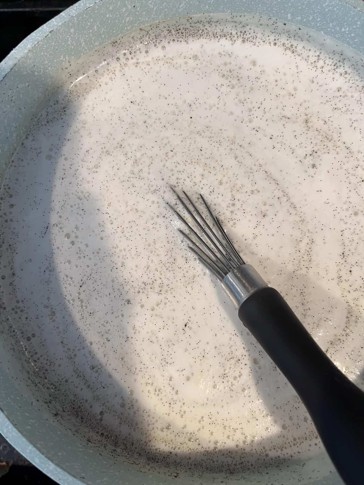 Whisking milk mixture with vanilla bean specks.