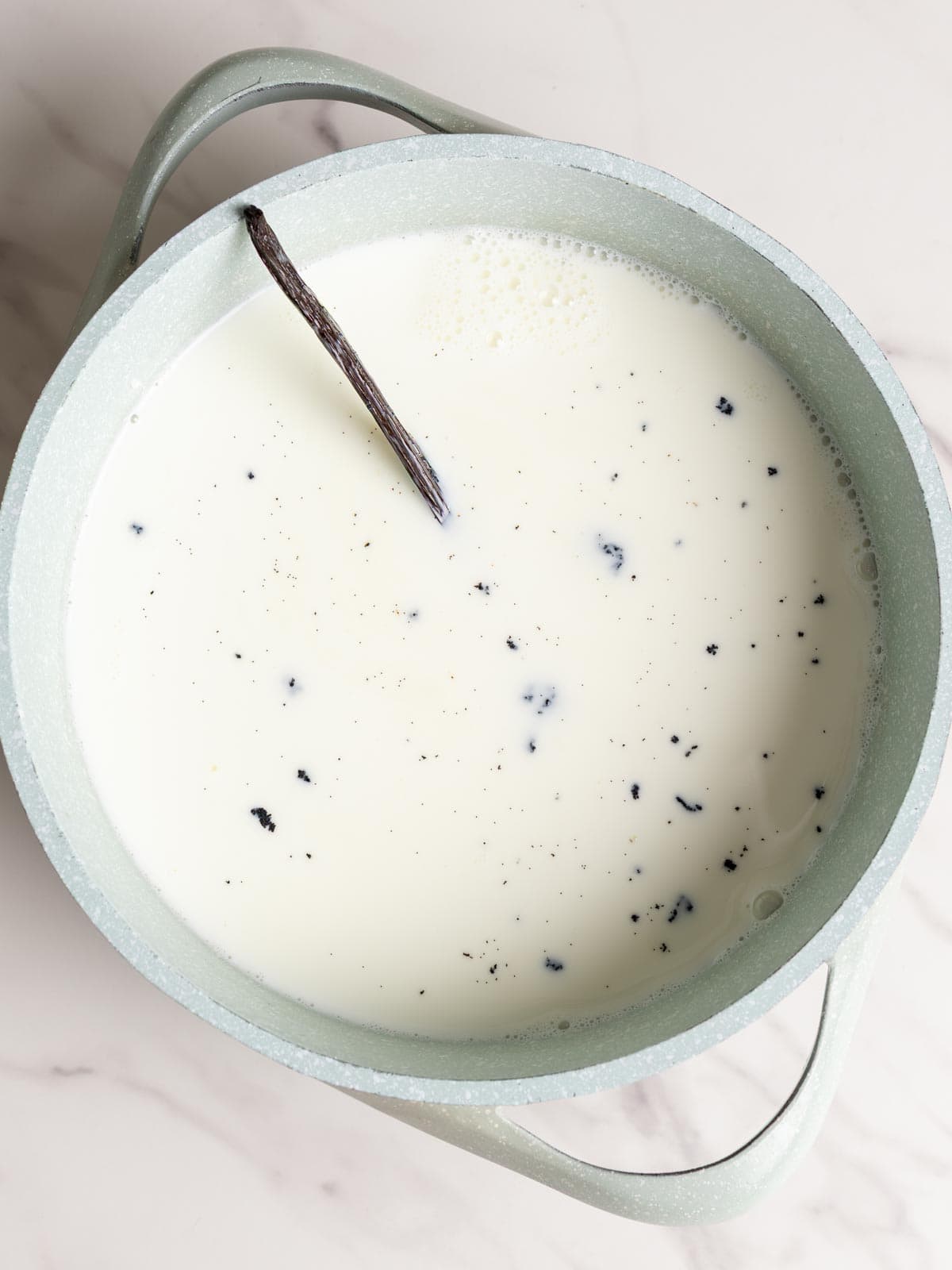Milk and vanilla bean pod in a pot.