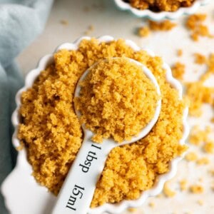 A cup of brown sugar with a tablespoon full in the middle.