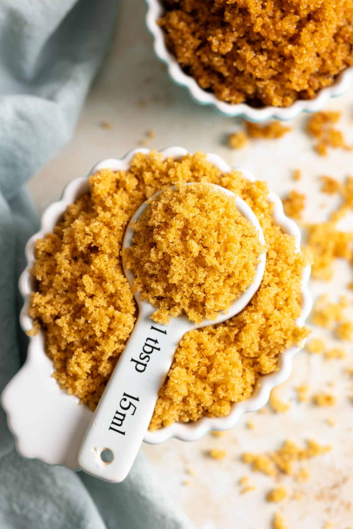 A cup of brown sugar with a tablespoon full in the middle.