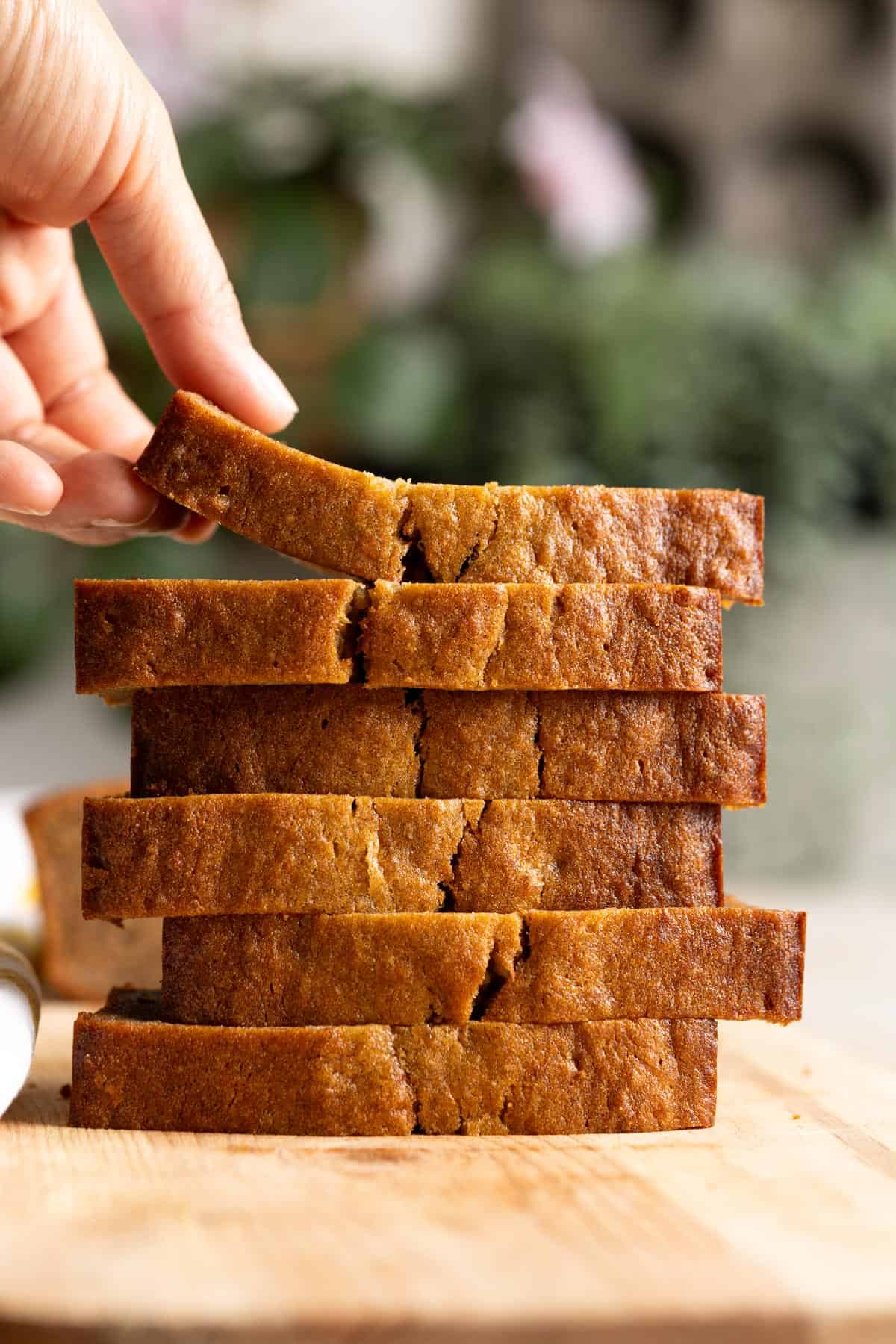 A stack of mochi banana slice with a hand lifting up the top slice.