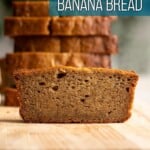 A slice of mochi banana bread on a cutting board with a stack in the back.
