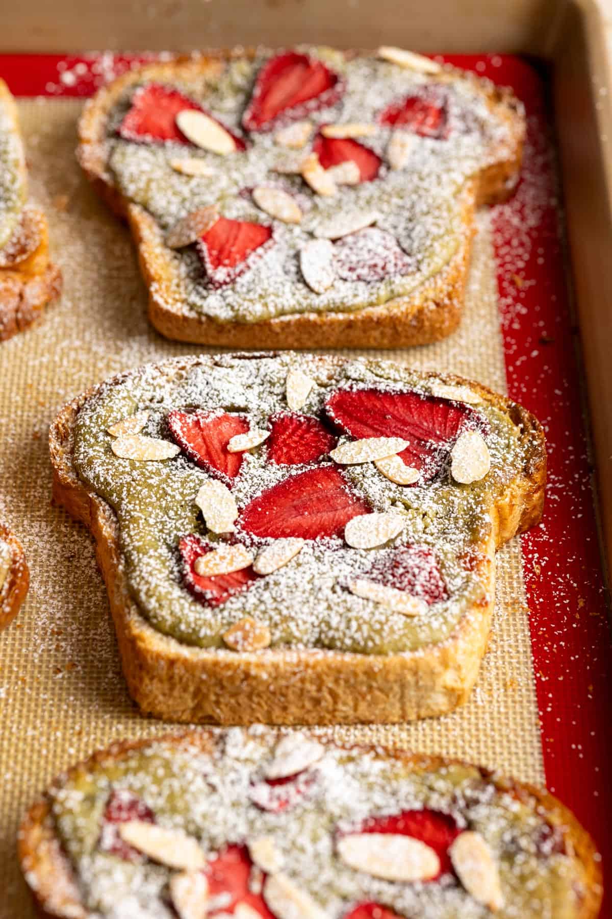 Matcha bostock pastries with powdered sugar on a baking sheet.