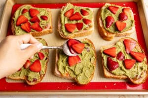 Spooning strawberries on top of matcha almond cream.