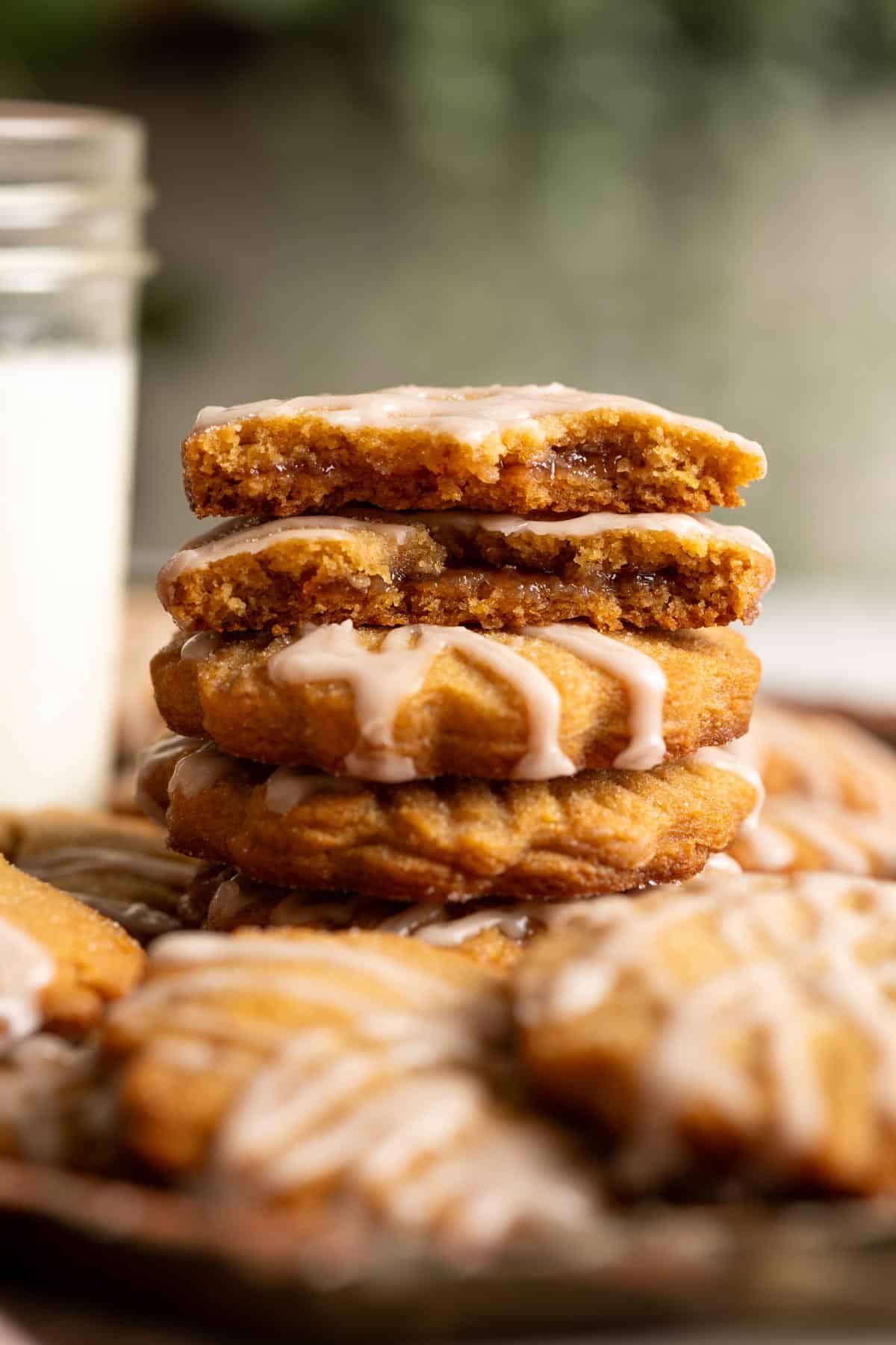 A stack of miso peanut butter and jelly sandwich cookies, the top ones are broken in half to show the jam filling inside.