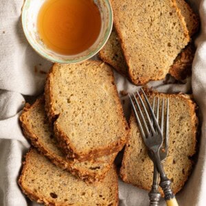 Slices of pineapple banana bread laying on top of each other next to a tea cup and 2 forks.