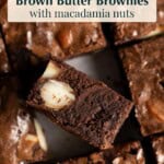 Brownies sitting on a flat surface, one is on its side showing the fudgy interior with macadamia nuts.